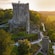 Blarney Castle on a hill surrounded by trees at sunrise